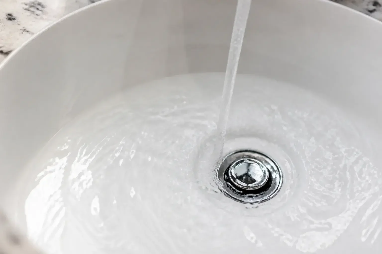 Pristine bathroom sink drain area with clear water flow